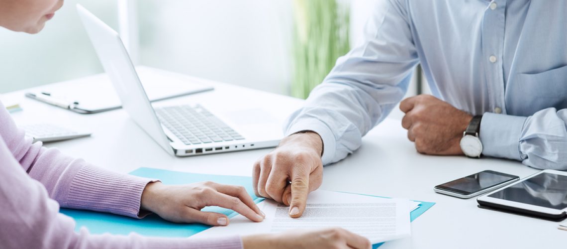 Young woman having a business meeting with an executive in his office he is pointing on a contract and giving explanations