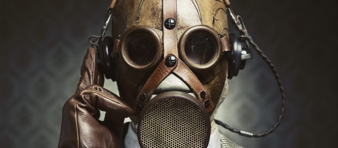 Man wearing vintage gas mask and headphones listening to music.