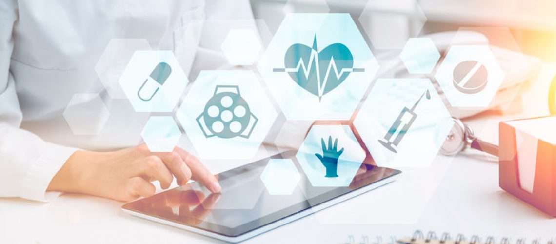 Doctor sitting at table and working with tablet. Medical icons in hexagonals in front. Only hands seen. Concept of medical help.