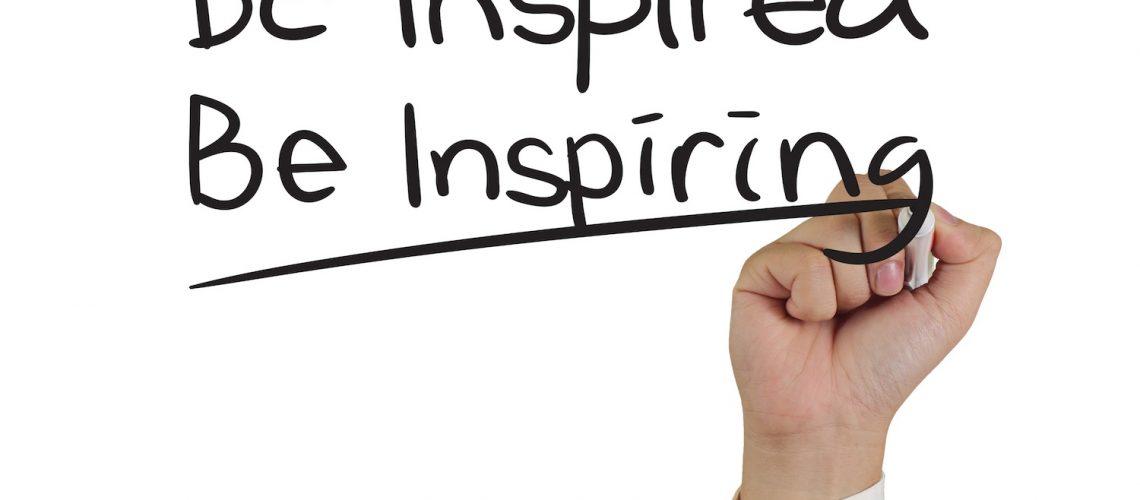 Motivational concept image of a hand holding marker and write Be Inspired Be Inspiring isolated on white