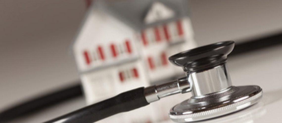 Stethoscope and Model House on Gradated Background with Selective Focus.